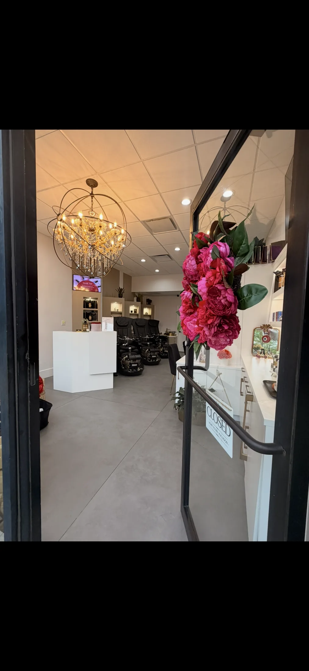 The entrance to Ridgewood Nail Club, framed by peonies with the orb chandelier beyond.